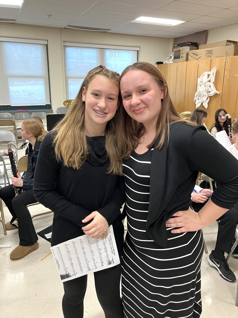 Two high school friends pose closely together in the music room