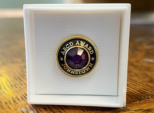 ABCD Award pin, closeup detailing purple gem and gold lettering