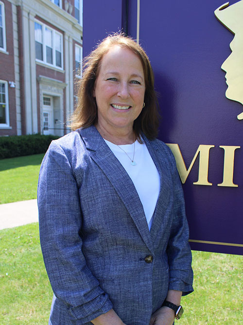 Becky Wager poses in front of Knox Middle School next to the entrance sign