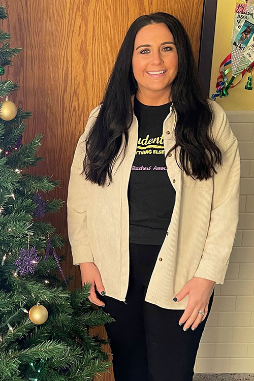 Jackie Strouse stands in a school hallway next to a Christmas tree