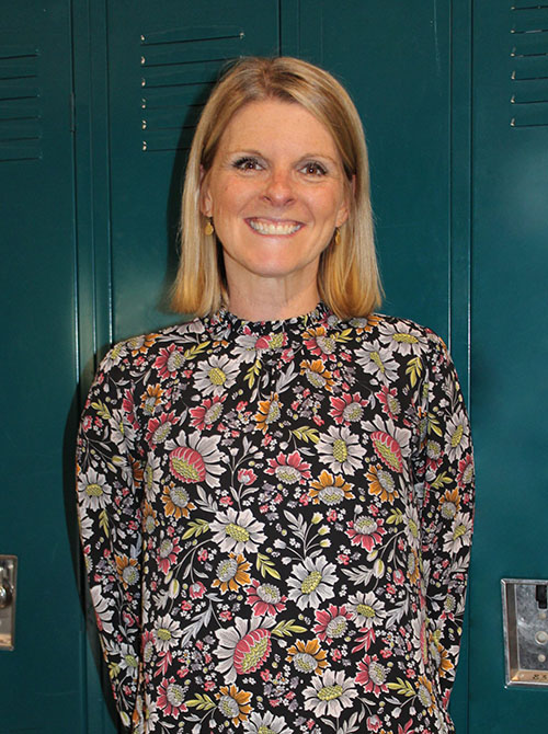 Jennifer Sweeney stands in front of lockers wearing a flowered blouse and smiling