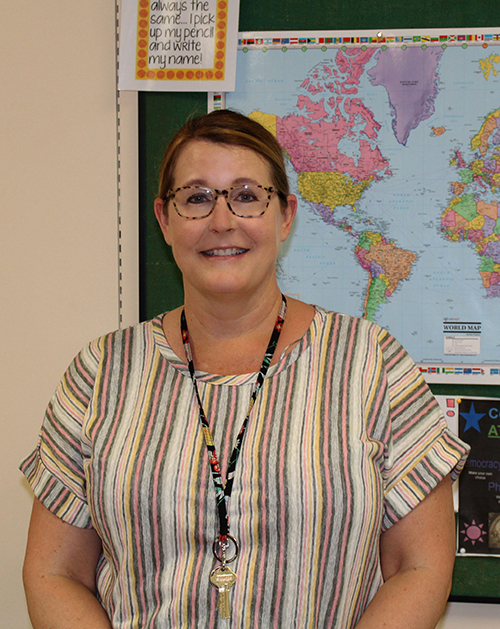 Jennifer VonderHeide stands in front of a world map