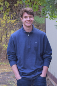a young man wears a blue sweatshirt in an outdoor setting