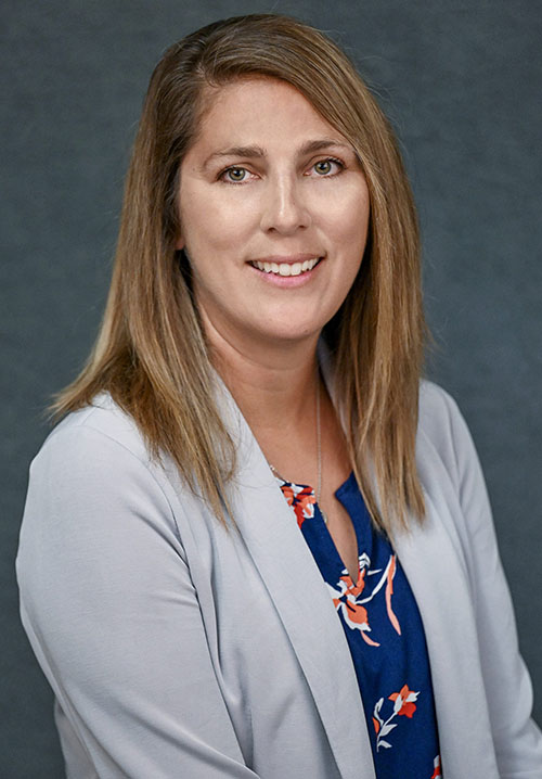 Nicole Panton headshot with floral blouse and grey blazer