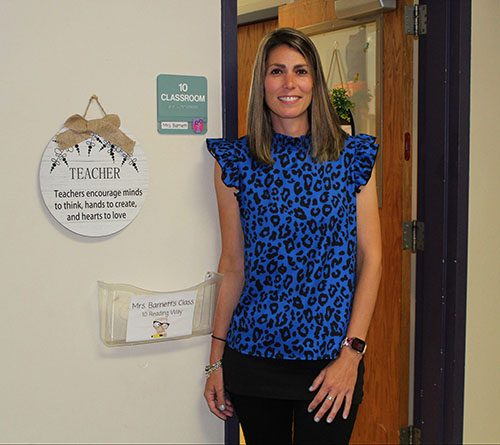 Olivia Barnett smiles next to the entrance to her classroom