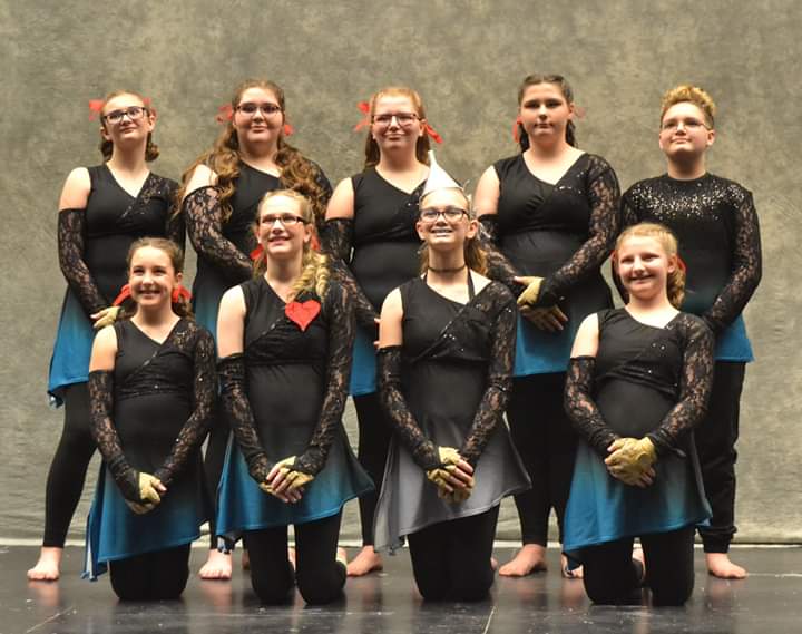 Nine members of the Winterguard team stand and kneel in two rows