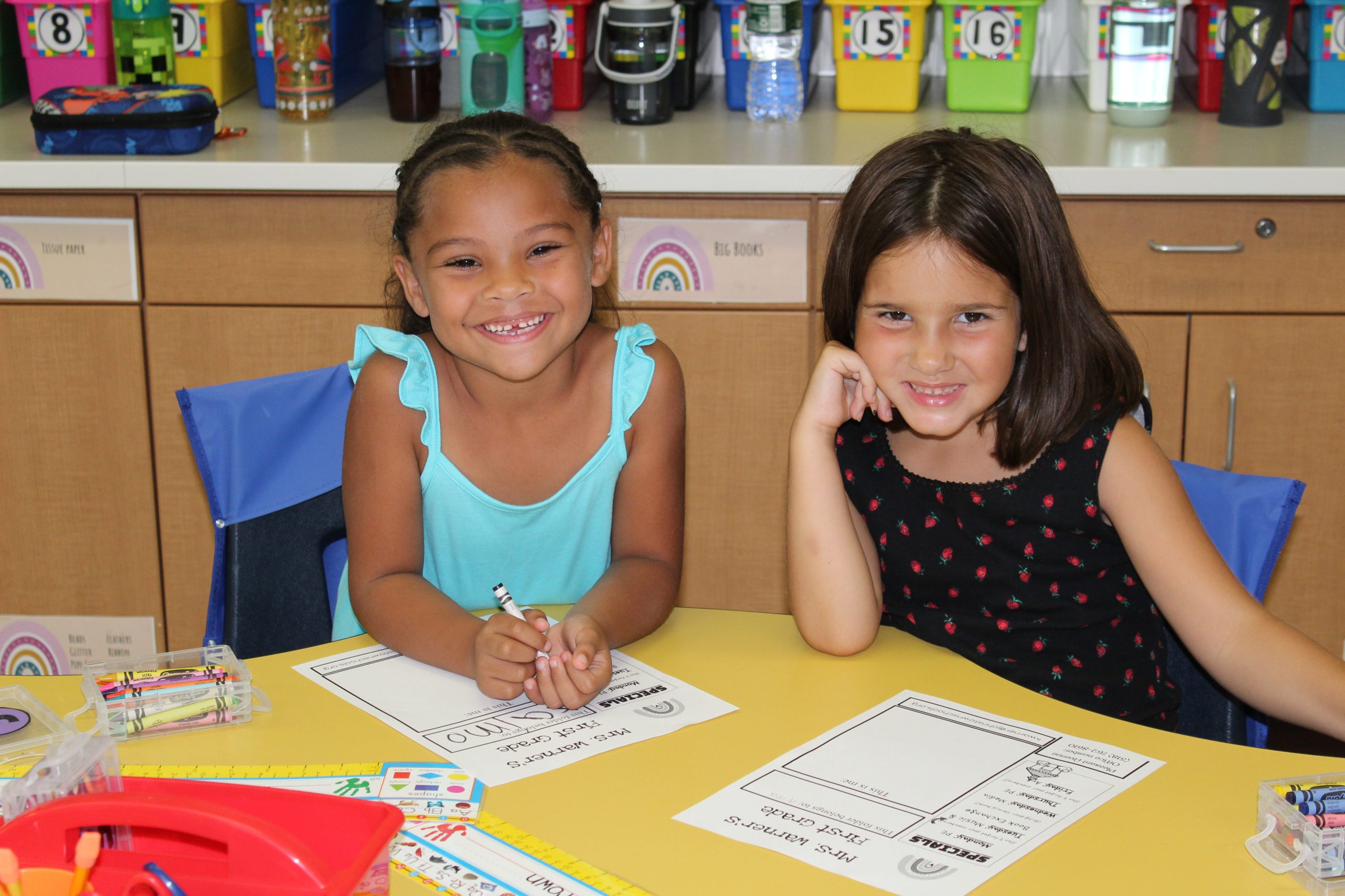 Two first grade students smile happily at a work table