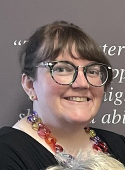 Board member Marjorie Kline headshot with black glasses and colorful necklace