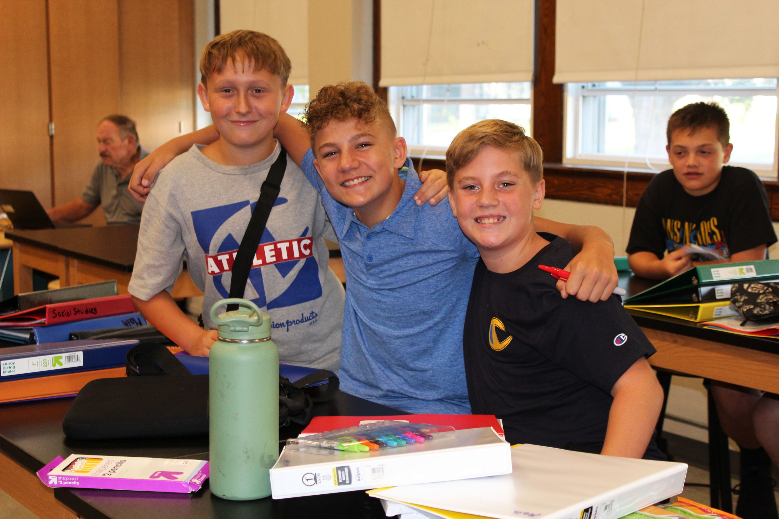 Three happy students pose together in a classroom