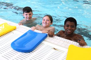 three young boys swim in a pool
