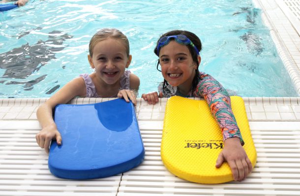 two young girls swim in a pool