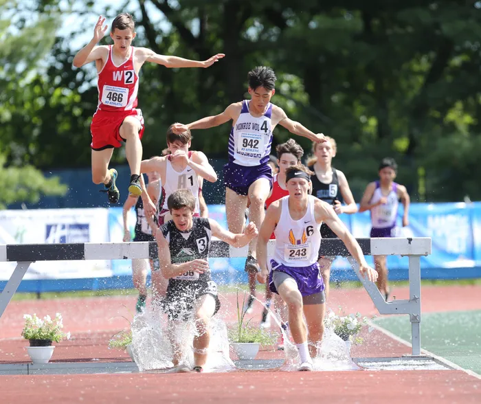 image of track and field athletes running through water and over a hurdle