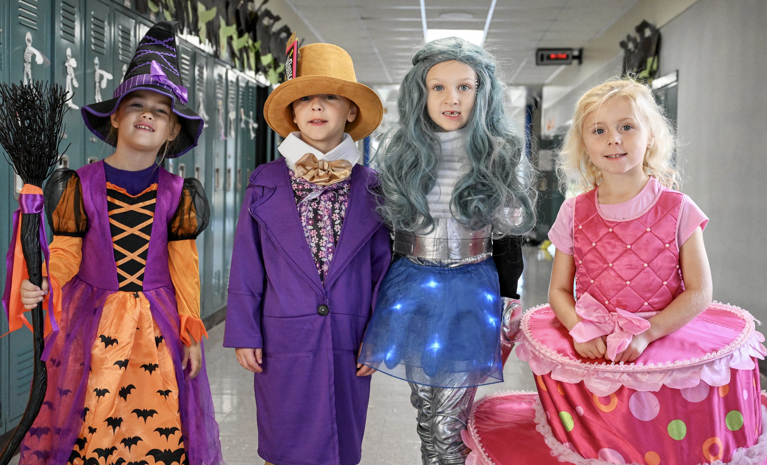 four young students dress up for Halloween and pose in the hallway of school