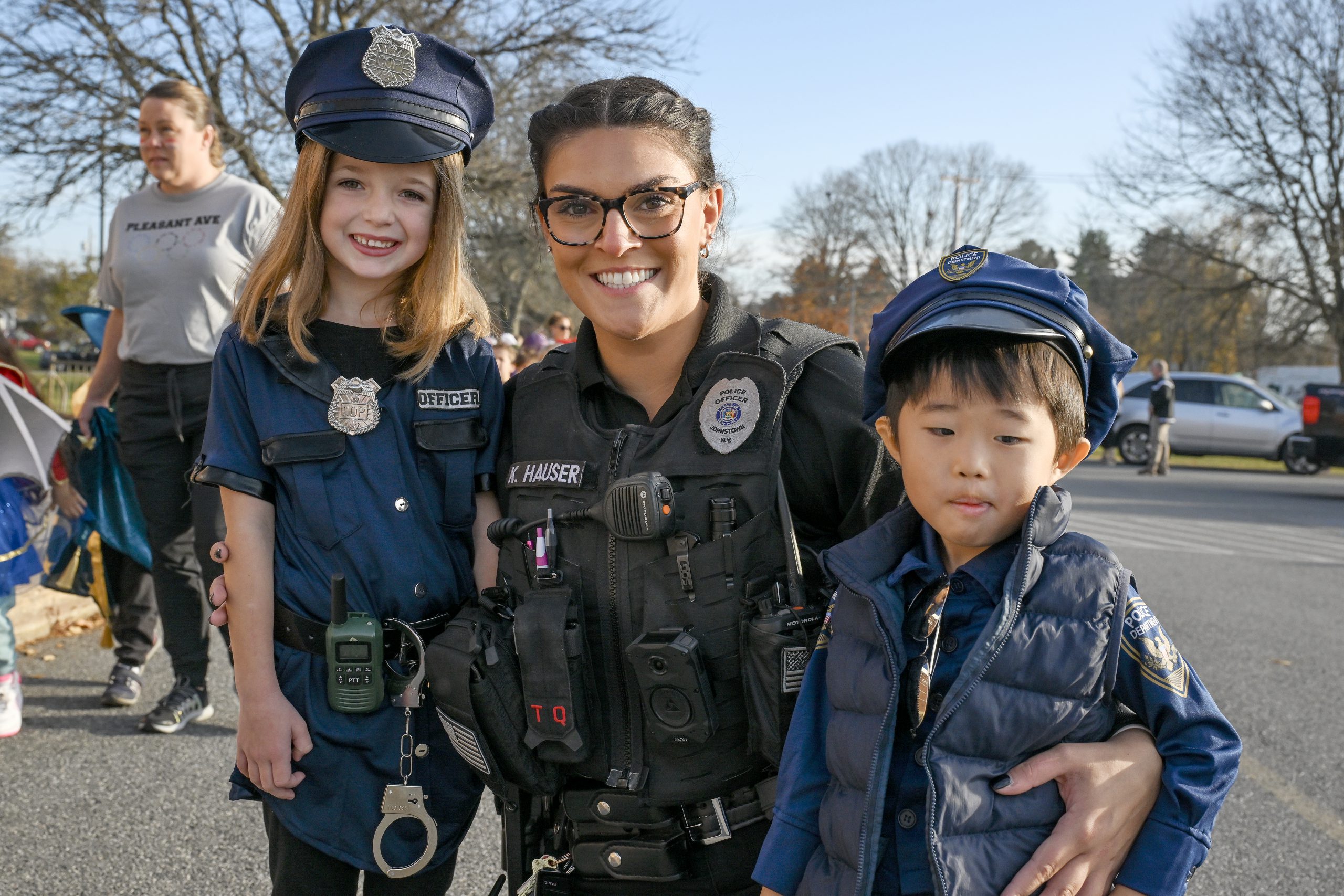 a police officer poses with two young children dressed up as police officers for Halloween