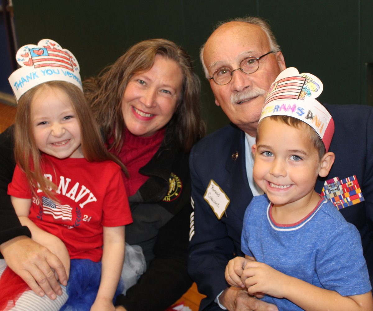 two adults pose with two young children in honor of veterans day