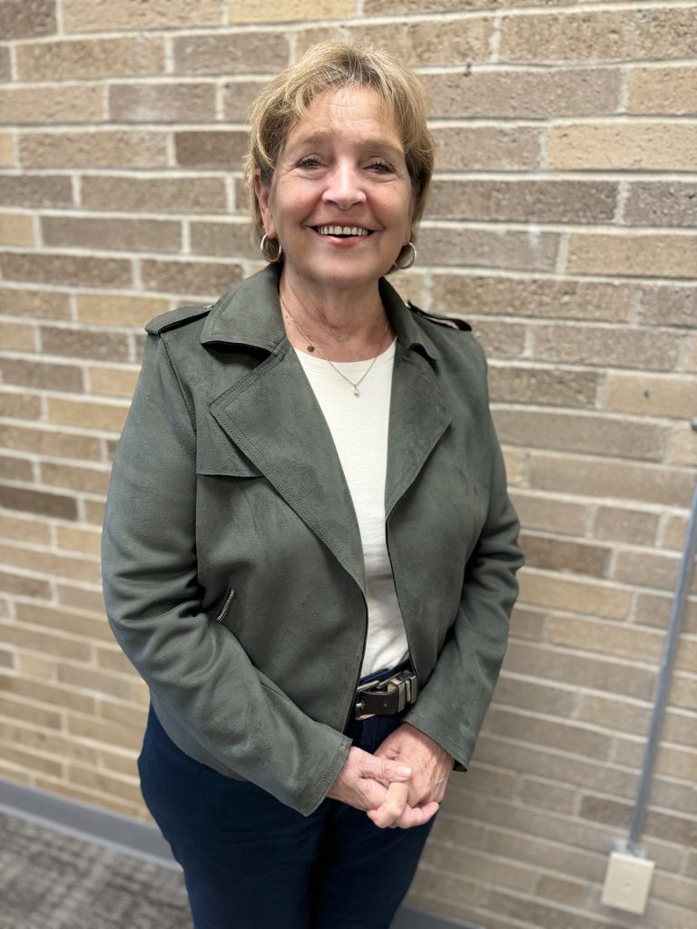 a woman poses in front of a brick wall