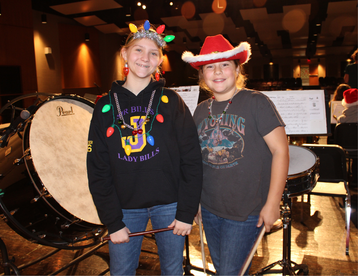 two teen girls pose with holiday hats on a theatrical stage