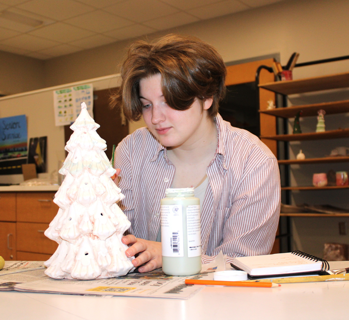 a teen student paints a ceramic Christmas tree