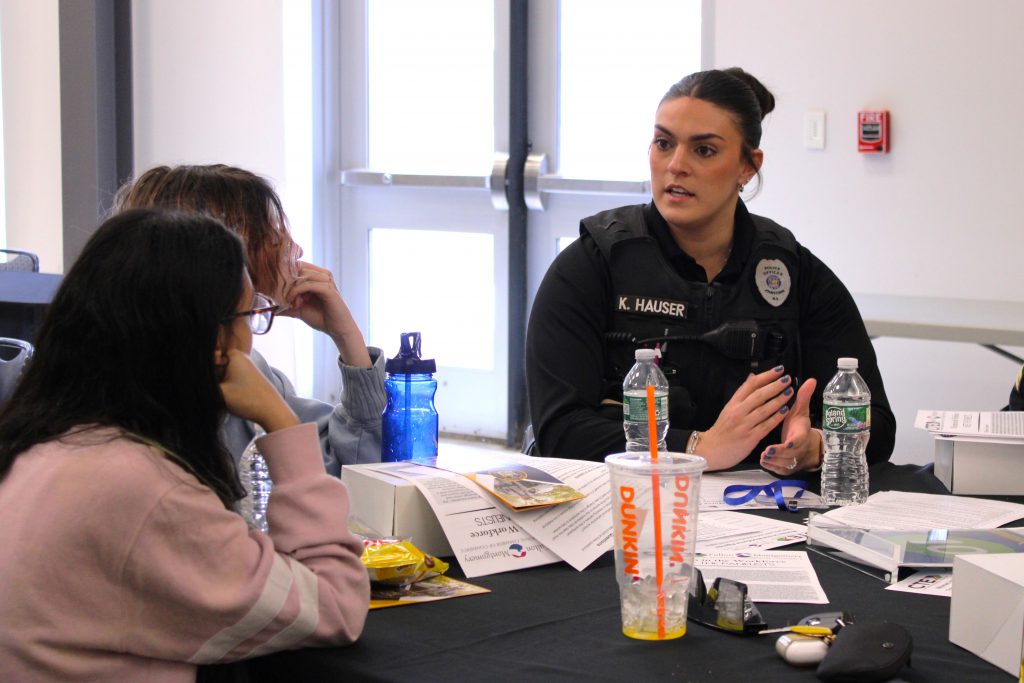 a police officer sits at a table and has a conversation with two young women