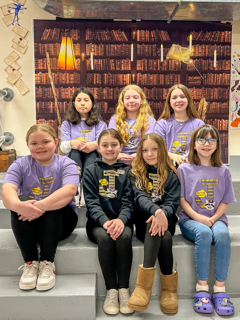 seven female middle school aged children sit and pose