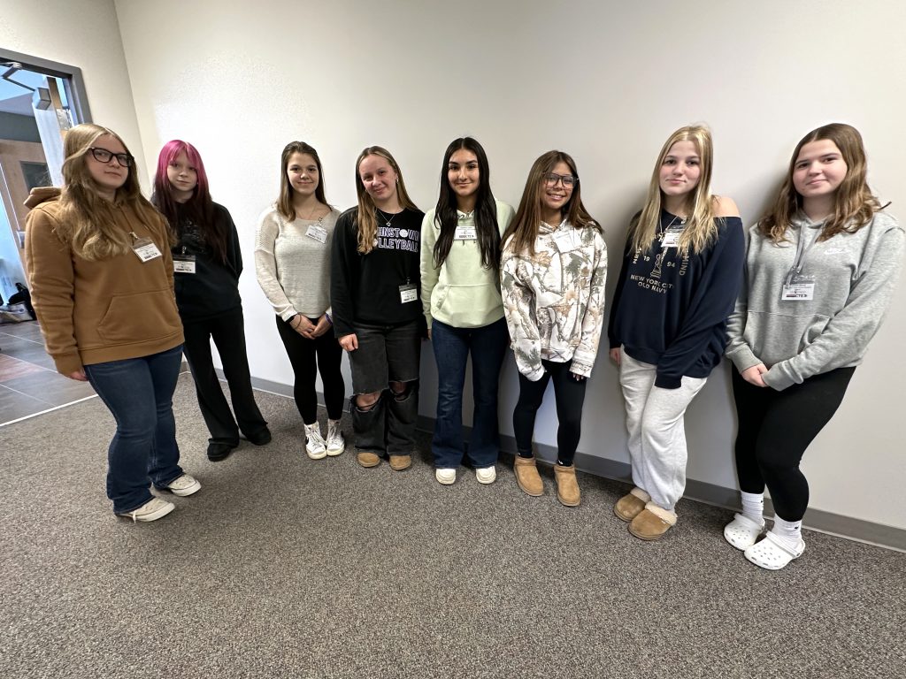 eight young female students pose in a hallway